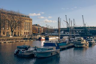 Scenic landscape of Bristol harbourside on a sunny winter afternoon with boats in foreground and Arnolfini international arts centre in background,