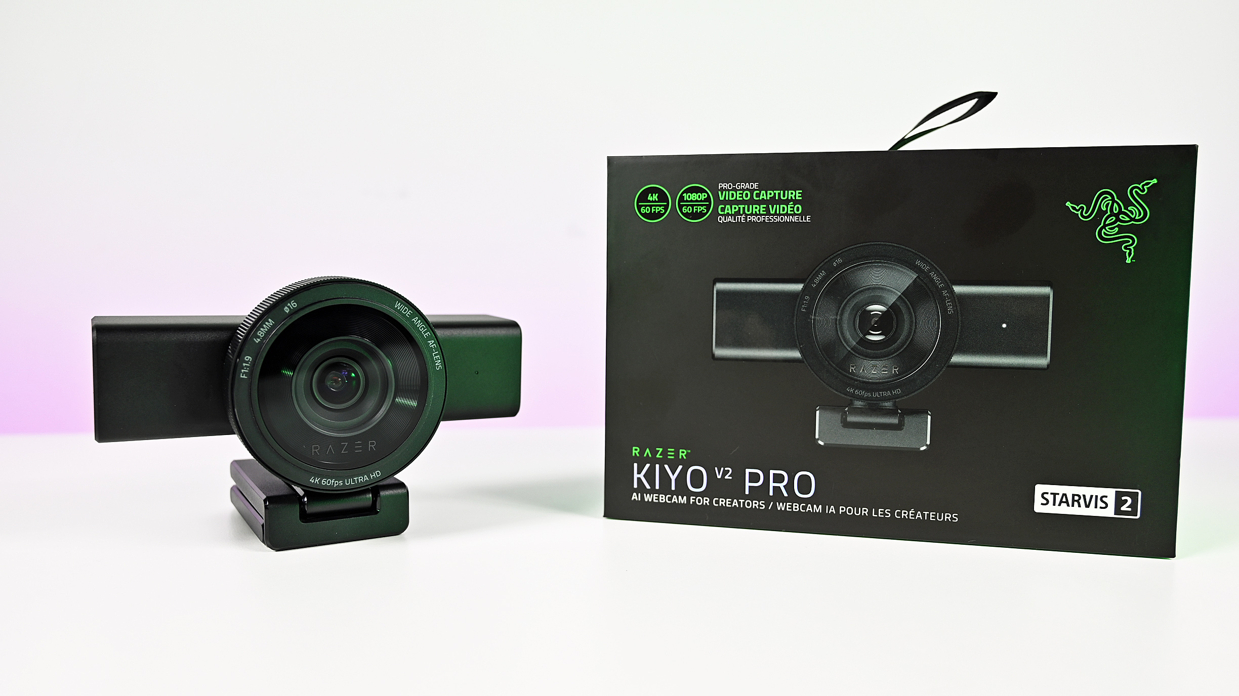 Razer Kiyo V2 Pro webcam on its monitor mount next to its black retail box under bright white studio lighting