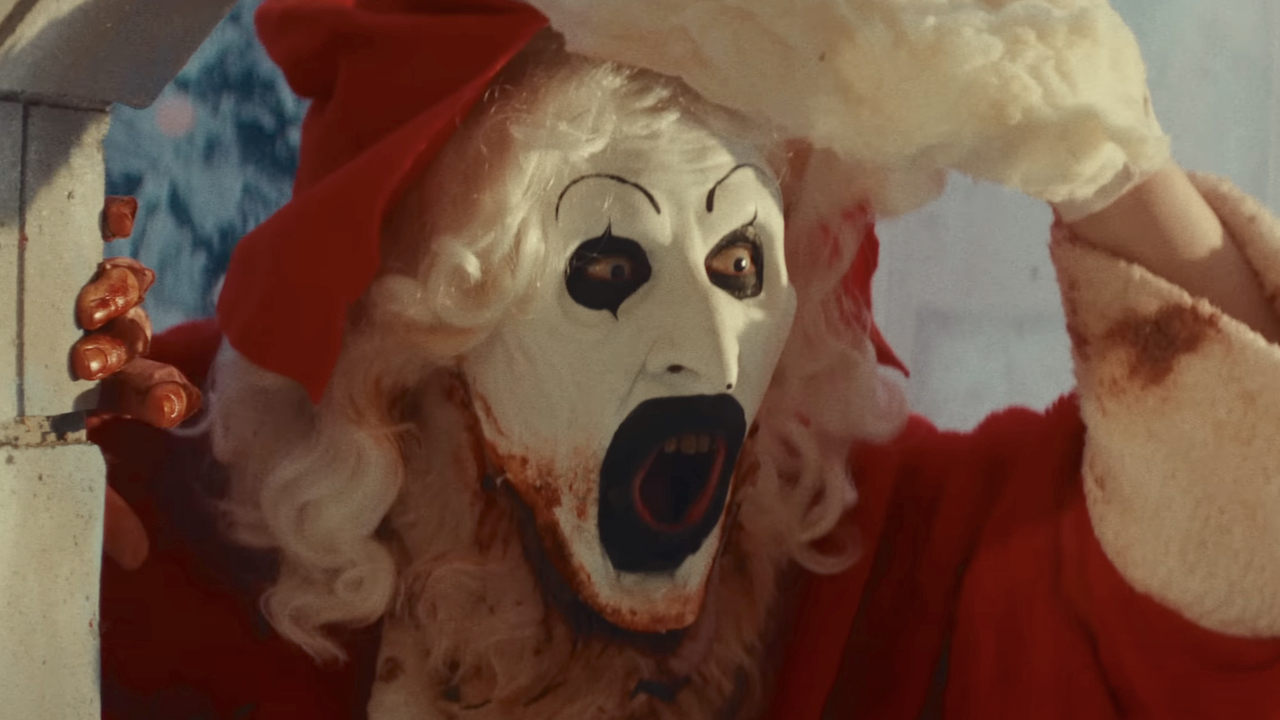 Screenshot of Art the Clown taking off the Santa Claus mask from his face in the movie 