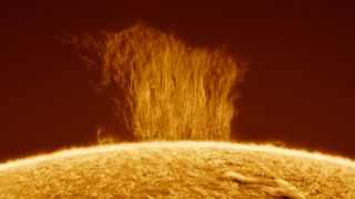 A wall of falling plasma rains down onto the sun with a black background