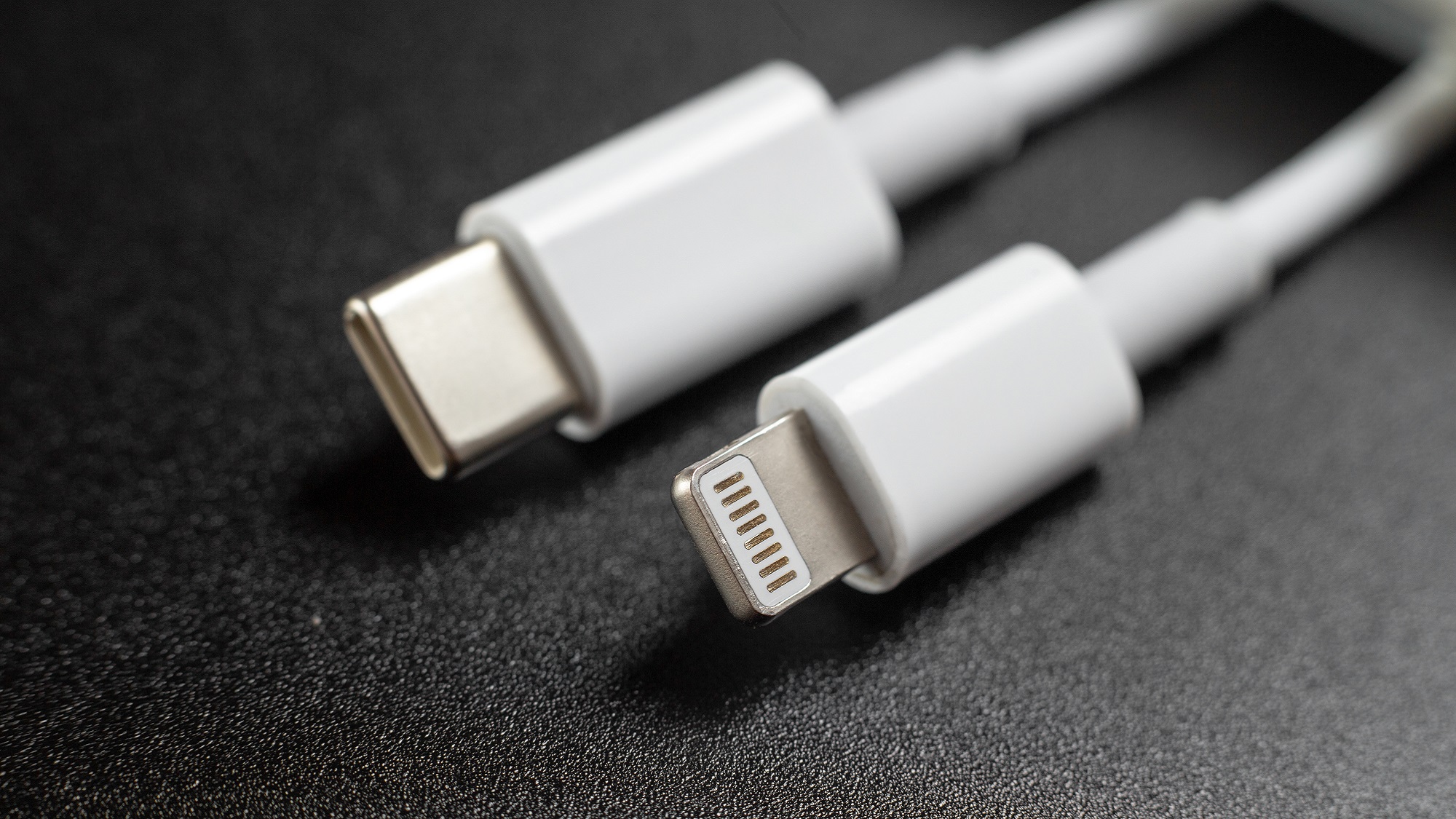 Зарядные кабели USB-C и Lightning для телефона на чёрном фоне