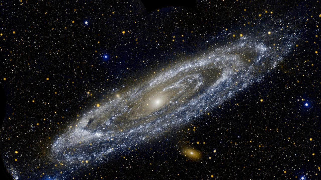 A spiral galaxy disk glows in the darkness of space