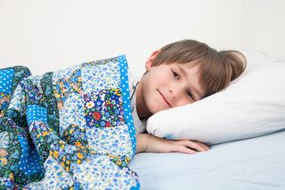 A little boy lies awake in his bed.