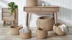A collection of large woven baskets on the floor in front of a console table 