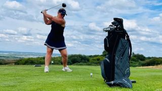 A golfer makes a swing with the Callaway Reva Ladies Package Set in front of her