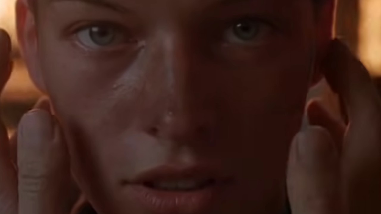 『メッセンジャー：ジャンヌ・ダルクの物語』で顔に手を当てるミラ・ジョヴォヴィッチ