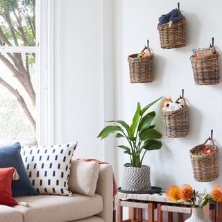 white living room with wall hanging baskets and beige sofa with colorful pillows and plant accessory