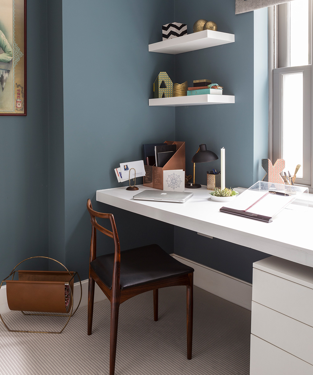 A built-in white desk and floating shelves in a dark blue-gray scheme.