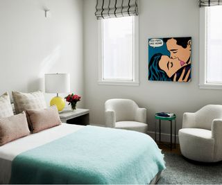 Bedroom with blue bed cover and contemporary art on wall