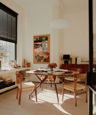 Scandi style office with wooden round table and wooden woven chairs, hanging pendant light, noticeboard with pictures