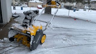 The Dewalt 60V Max Single-Stage Snow Blower in a snowy yard