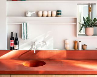 Small kitchen with white walls and orange surface with open shelving