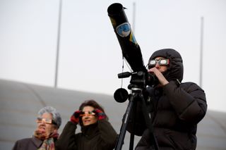 Skywatchers observe a partial solar eclipse