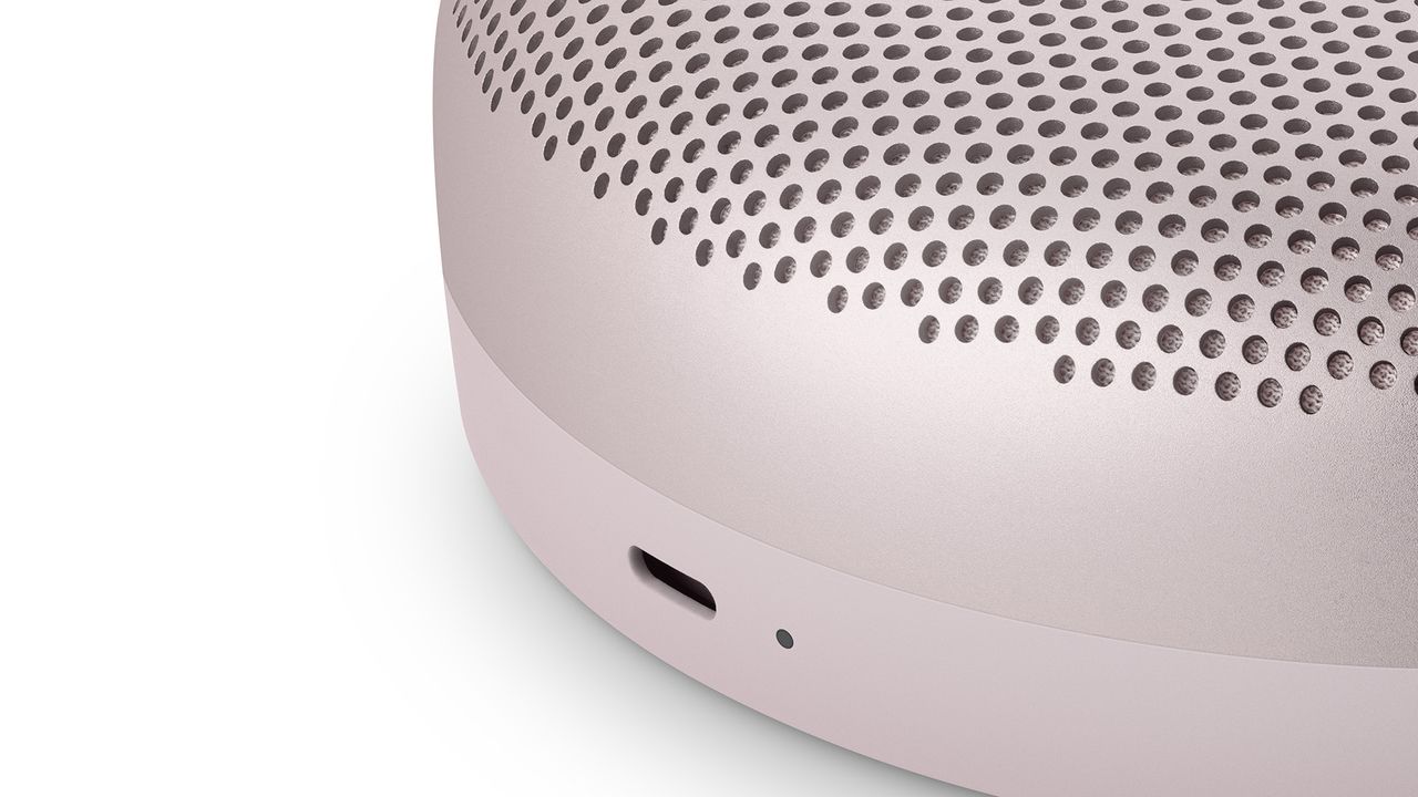 A close-up of the USB-C port on a pink Bang &amp; Olufsen Beosound A1 (2nd Gen) speaker. The background is white.