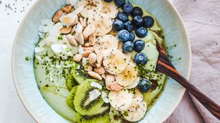This shows one way to eat kiwi is adding it to a yoghurt or porridge bowl with other things like banana and coconut shavings