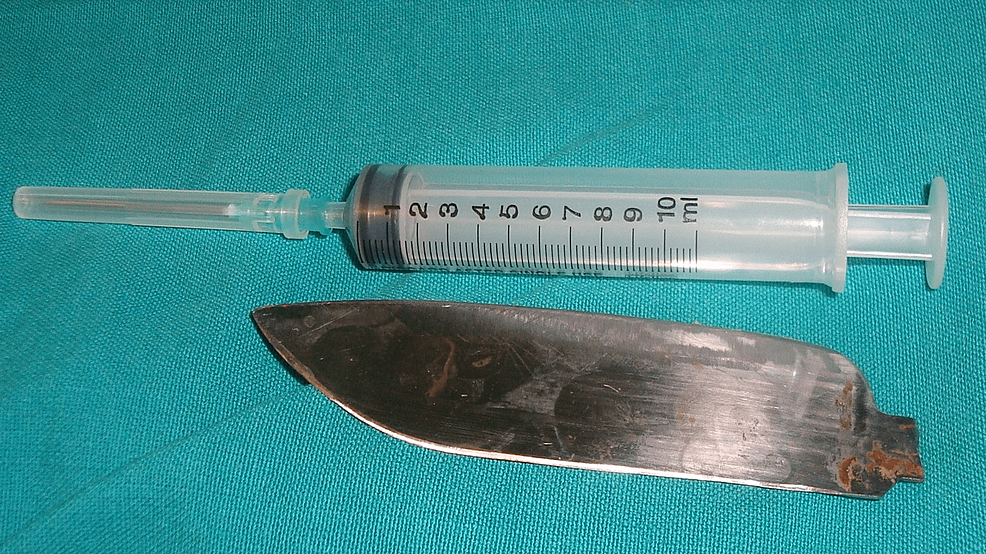 The extracted knife blade next to a 10 ml syringe for comparison