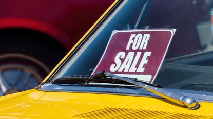 A bright yellow car has a "for sale" sign in the front window.