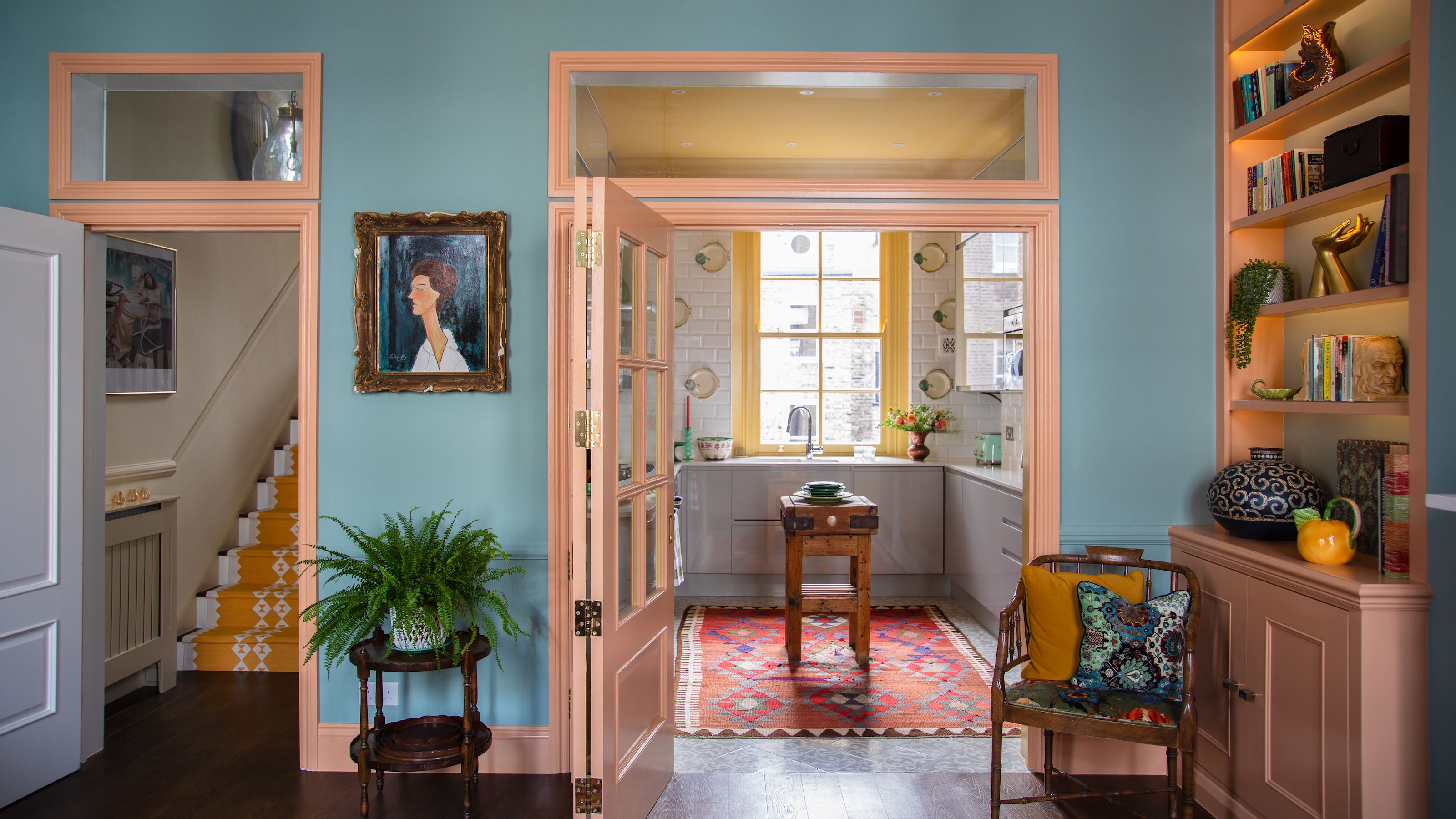 view through to kitchen from room with blue walls and door framed painted in pink