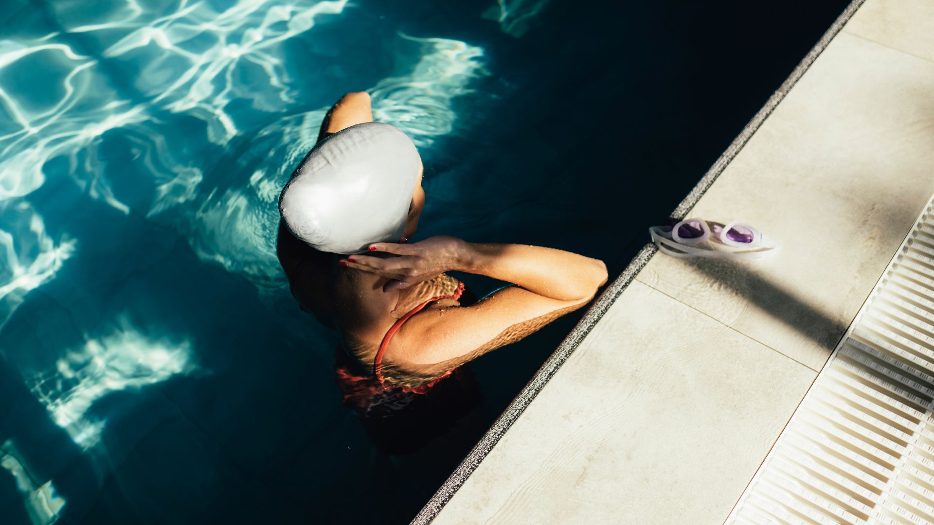 Woman fixing swimming hat in pool