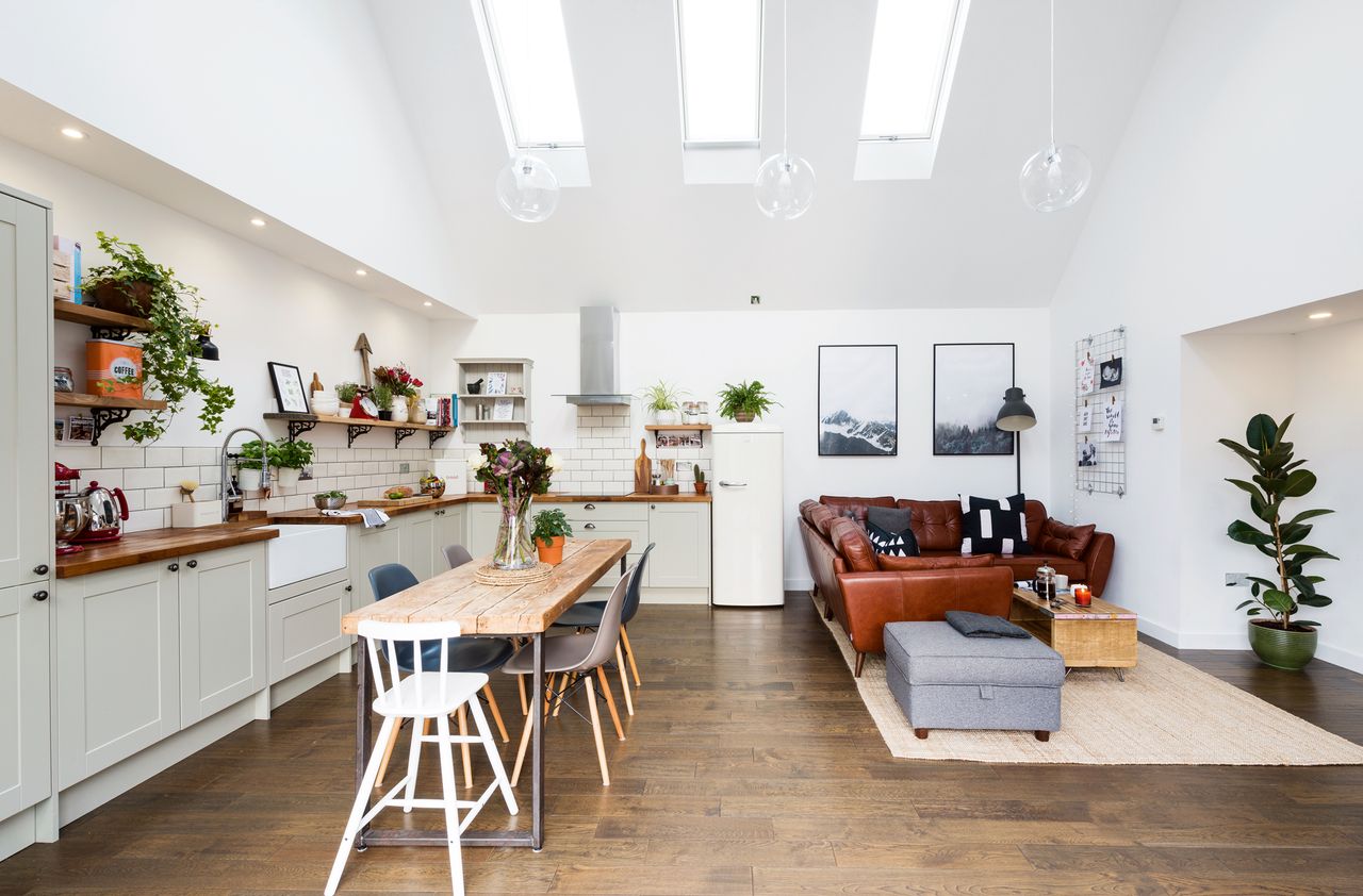 Home renovation with a double-height kitchen diner extension with rooflights, built-in kitchen units, a family dining table and a comfy seating area