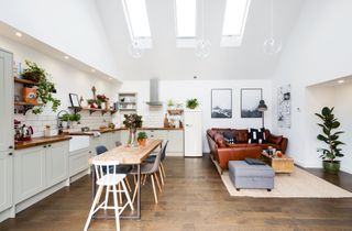 A double-height kitchen diner extension with rooflights, built-in kitchen units, a family dining table and a comfy seating area