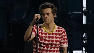 Harry Styles in red hearts shirt performing Satellite live