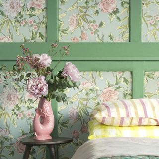 Floral wallpaper and vase of peonies at bedside table