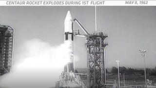 a black and white image shows a thick rocket lifting off from an adjacent launch tower, gases venting from the fuselage.