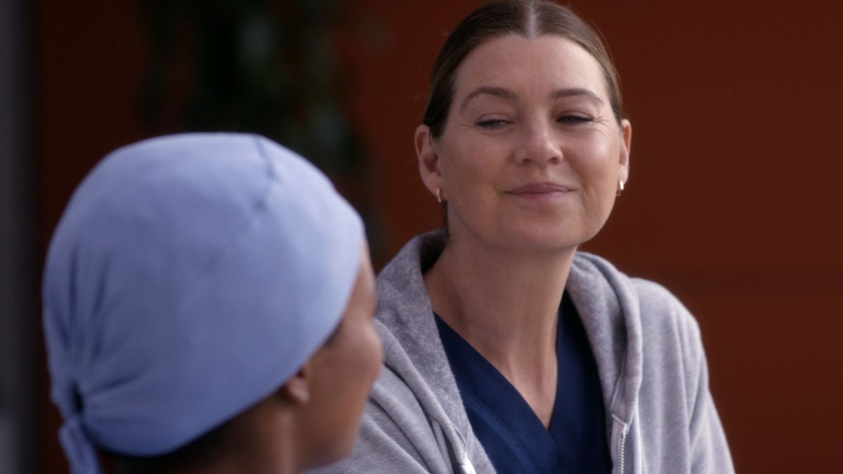 Ellen Pompeo smiling while sitting at the hospital in Grey&#039;s Anatomy season 19