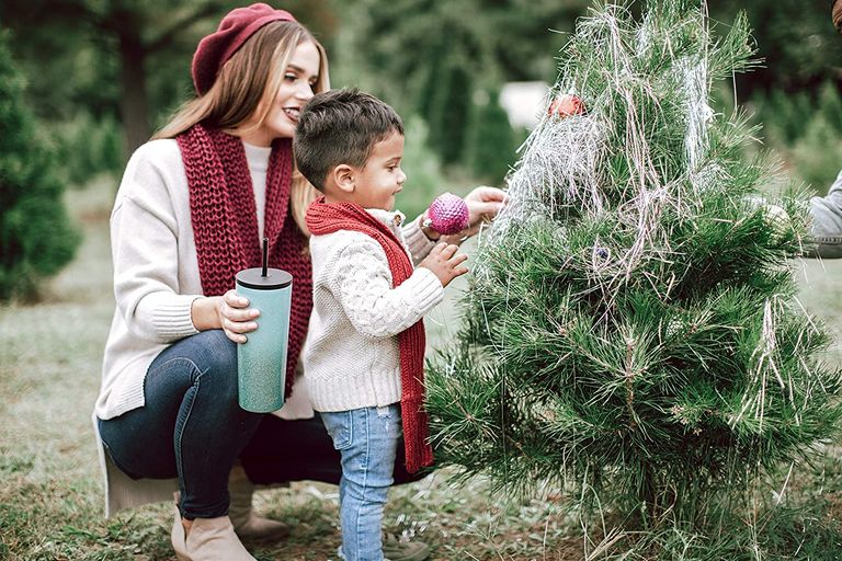 woman holding Simple Modern tumbler whilst looking at a Christmas tree outside with a baby