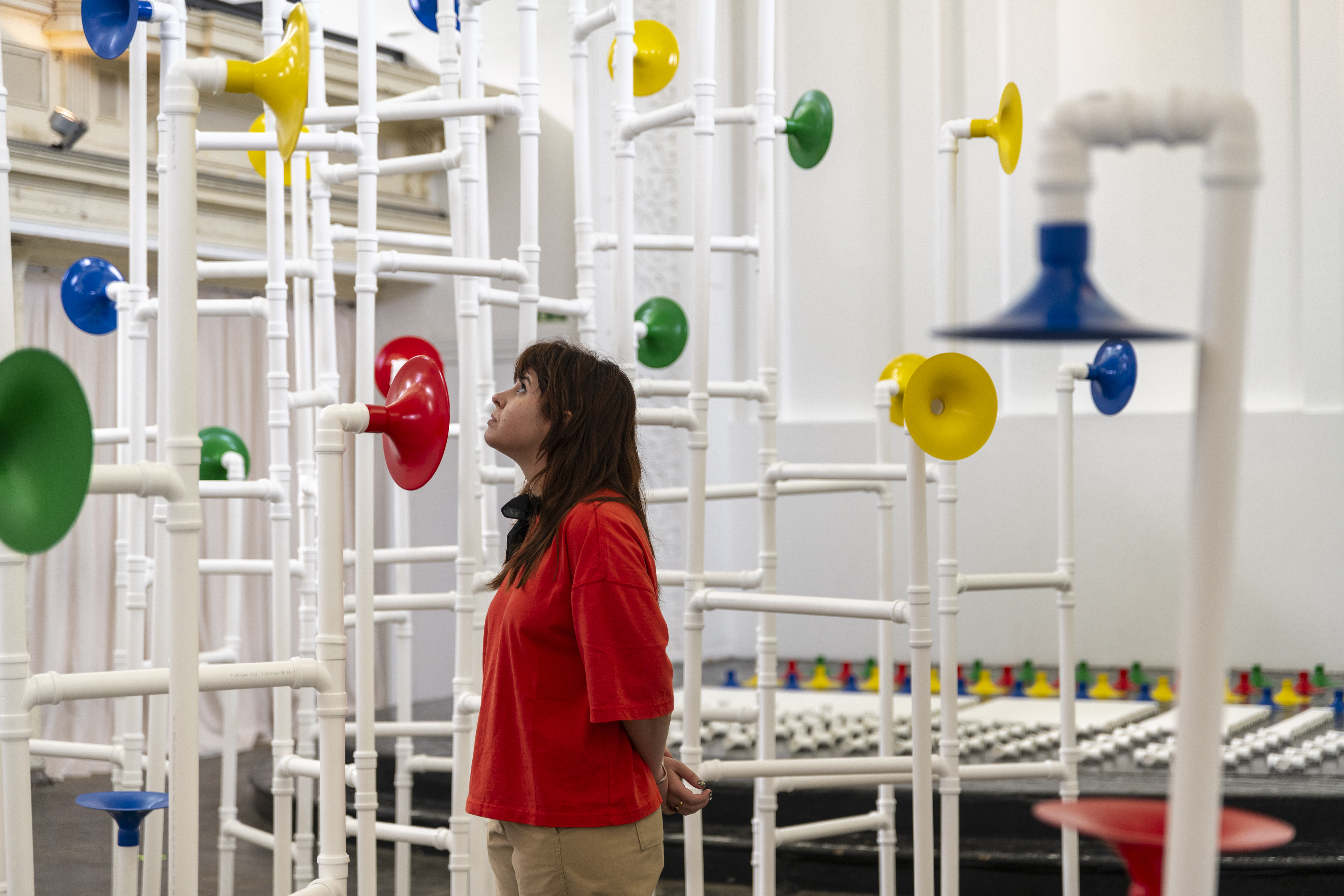 Installation in a former church made out of white pipes and colourful funnels