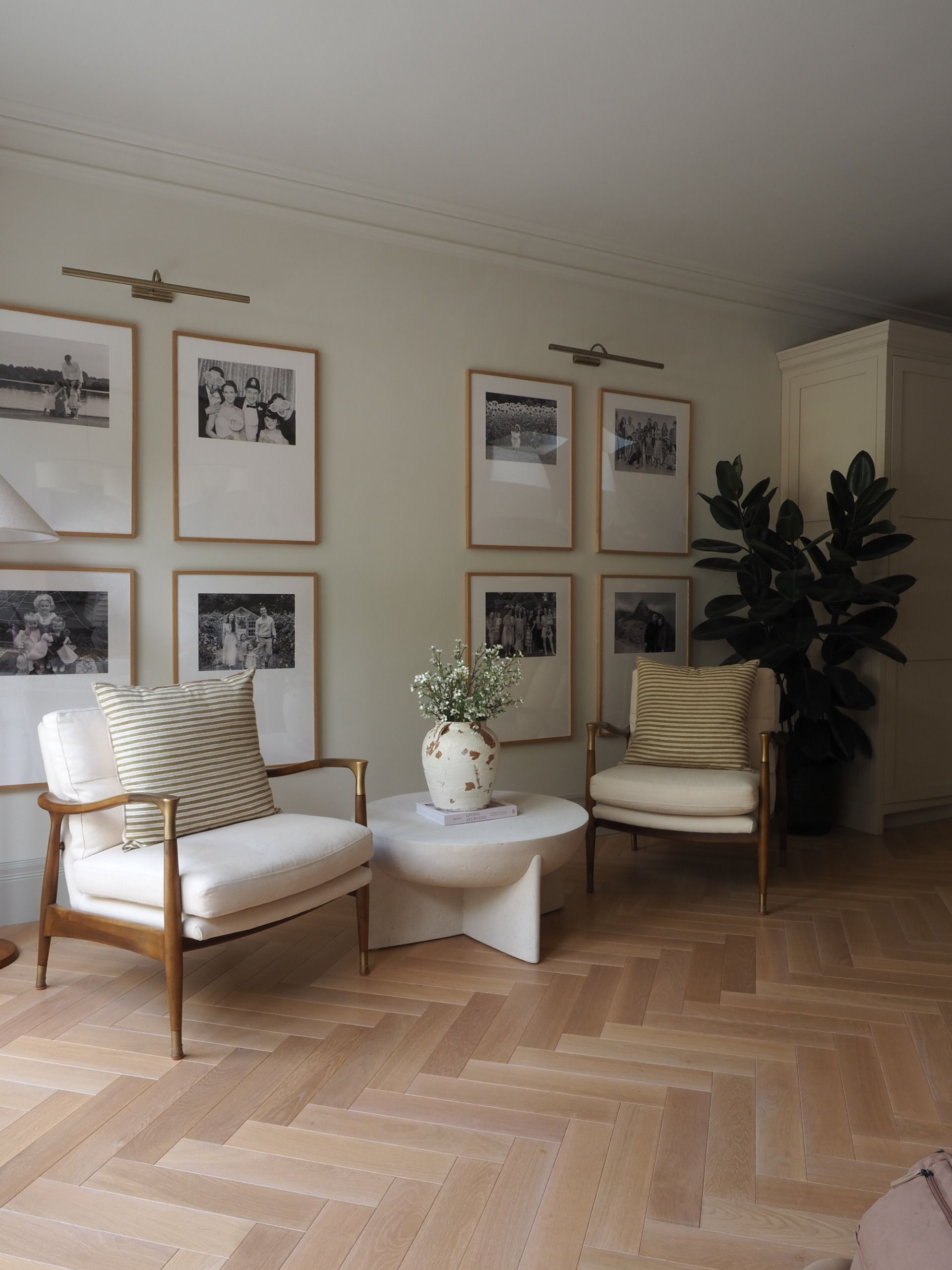 a seating area in a kitchen with a gallery wall of family photos and two armchairs