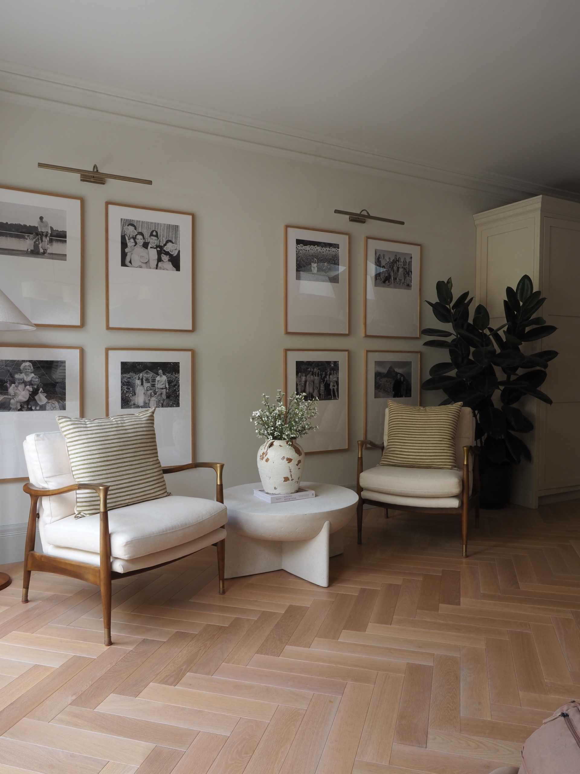 a seating area in a kitchen with a gallery wall of family photos and two armchairs