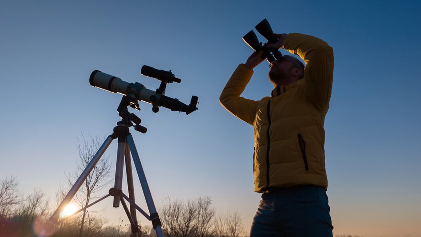 man using binoculars and a telescope at dusk