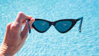 person holding sunglasses over pool