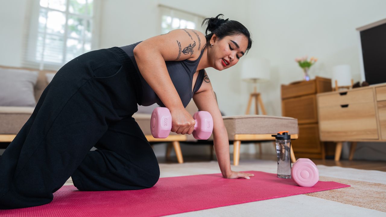 Woman doing dumbbell workout at home in living room