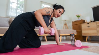 Woman doing dumbbell workout at home in living room