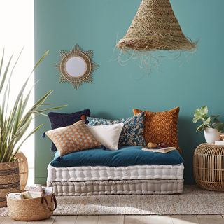 Blue wall with rustic accessories, green plants and colorful pillows