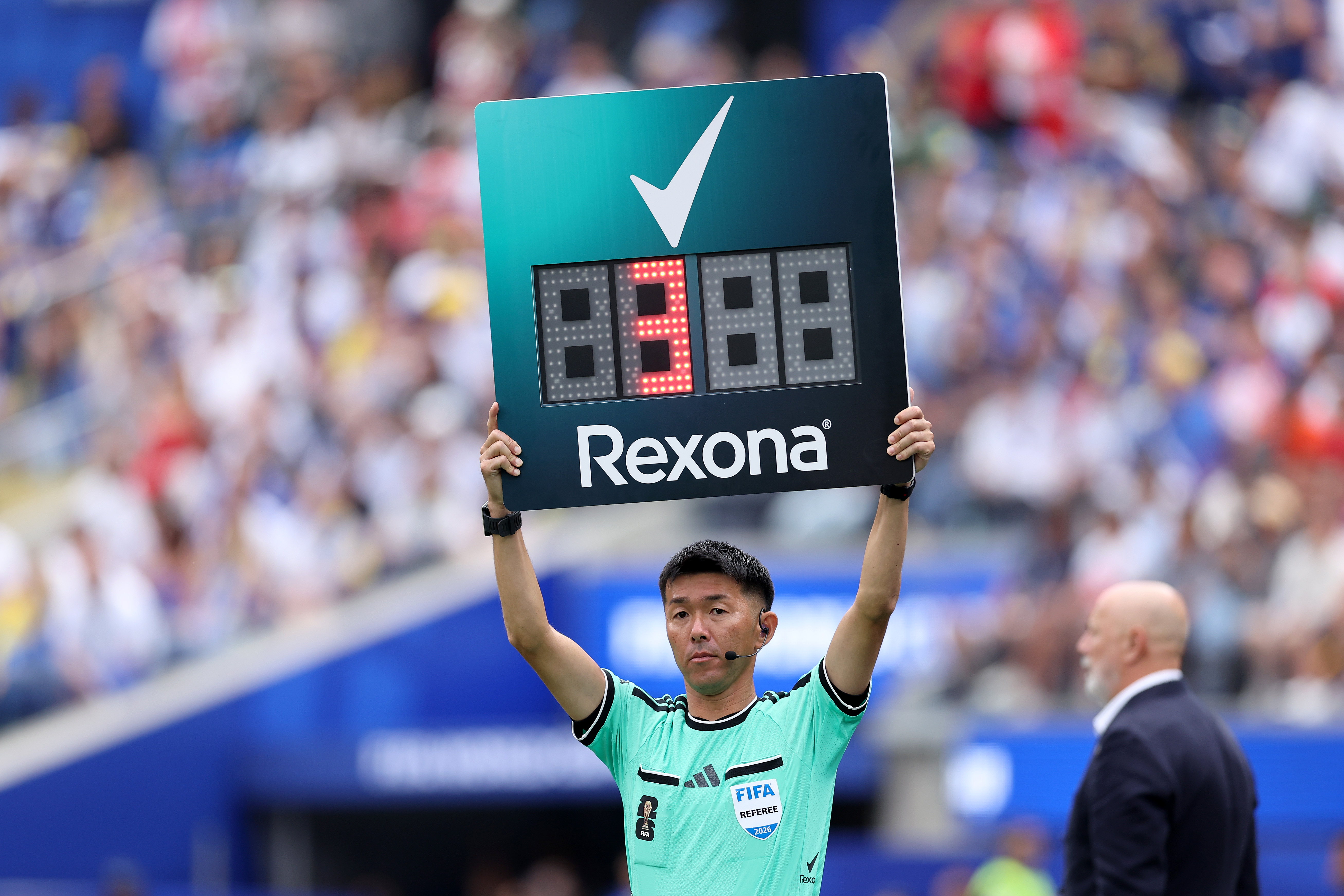INGLEWOOD, CALIFORNIA - JUNE 18: Fourth official Yusuke Araki holds up the Rexona substitution board during the FIFA World Cup 2026 Group B match between Switzerland and Bosnia and Herzegovina