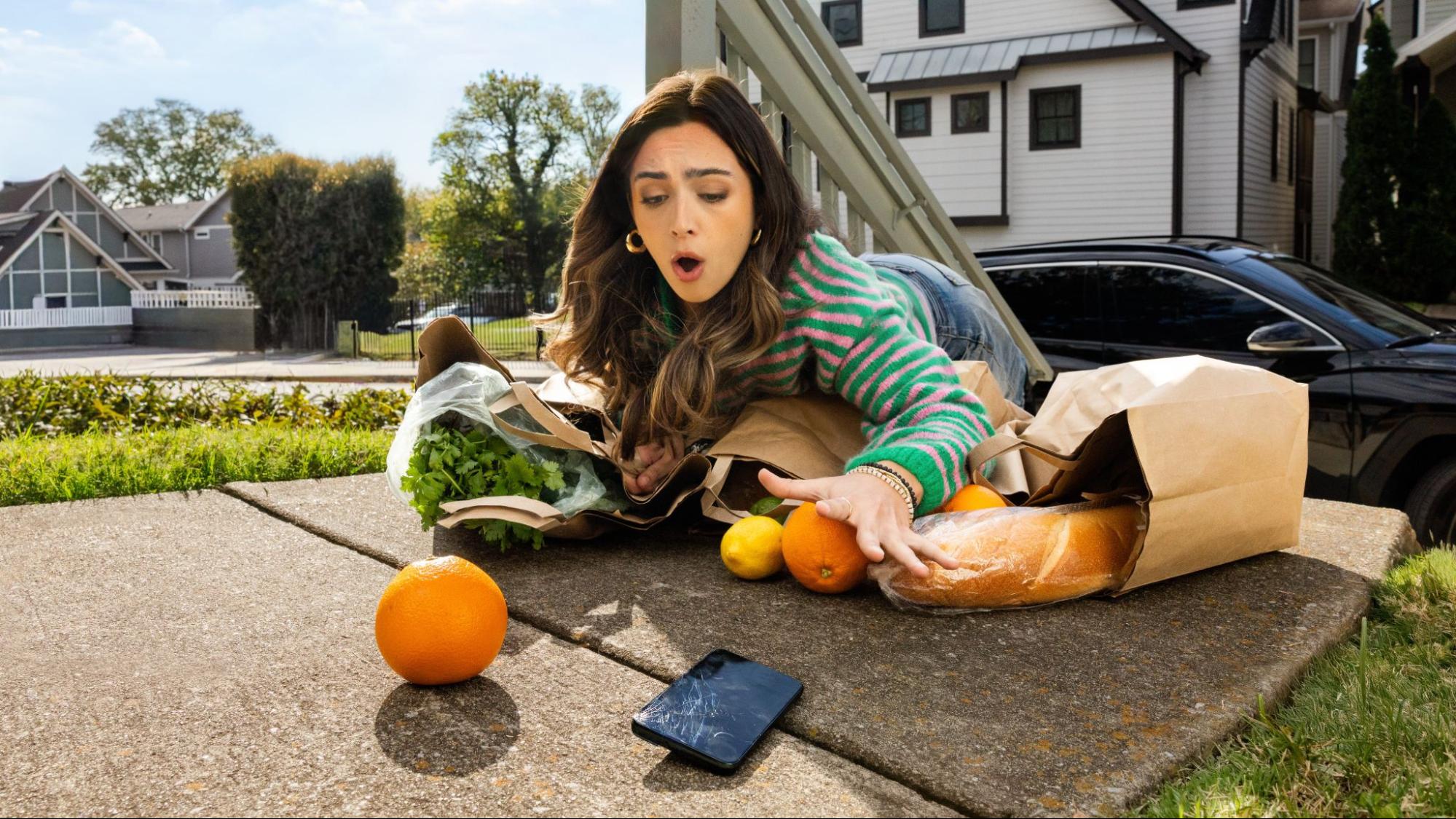 A woman falling, her phone breaking on the concrete.