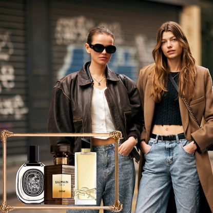two woman in blue jeans with long hair with a gold frame around three perfume bottles