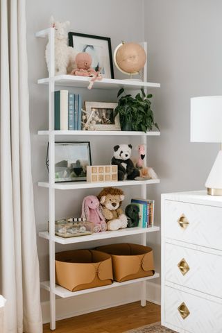 gray kids bedroom with ladder wall unit on wall with toys and books, chest of drawers to one side