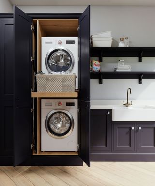 washer and dryer stacked on top of one another in dark grey laundry room