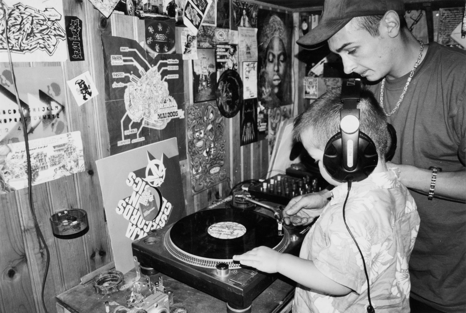 Black and white 1990s photo of man showing a young boy a turntable