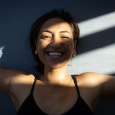 Let Them theory: A woman smiling in the sunshine on a yoga mat