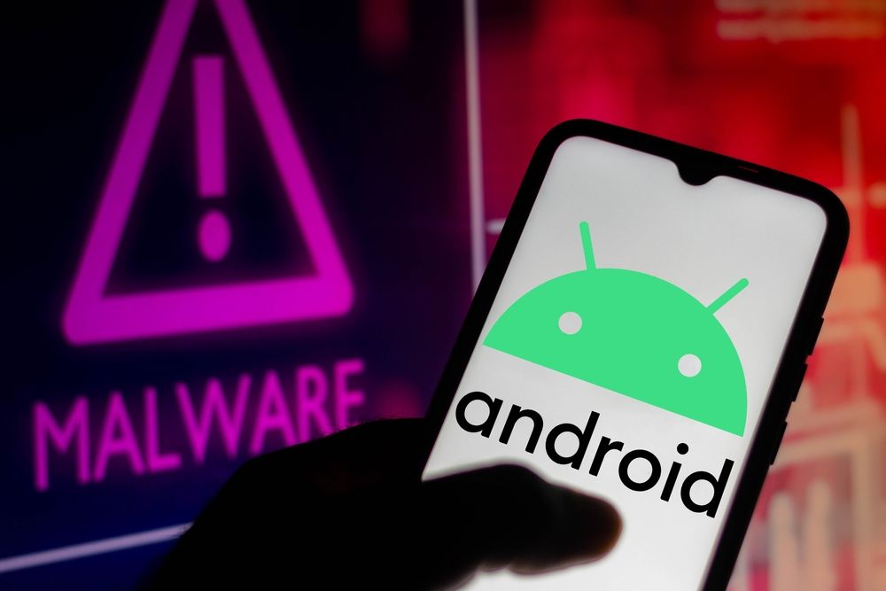 A smartphone screen displaying the Android name and logo next to a sign reading &#039;MALWARE&#039;.