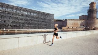 fit female runner running in an urban environment wearing the Polar Pacer Pro