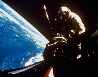 Astronaut Richard F. Gordon Jr., pilot for the Gemini-11 spaceflight, returns to the hatch of the spacecraft following extravehicular activity (EVA) on Sept. 13, 1966. This picture was taken over the Atlantic Ocean at approximately 160 nautical miles above Earth's surface.