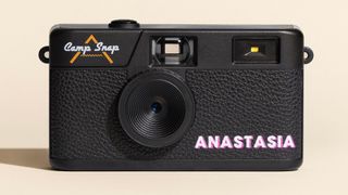 Personalized Camp Snap camera with a name on it, with strong studio lighting and a cream colored backdrop