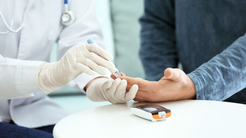 Gloved doctor pricks a patient&#039;s finger to conduct a blood sugar test